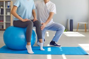 Physical therapist helps patient work on balance ball